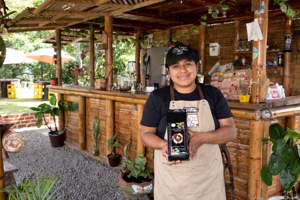Trabajadora con un delantal mostrando el empaque de un Café