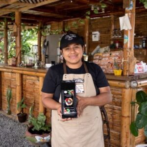 Trabajadora con un delantal mostrando el empaque de un Café
